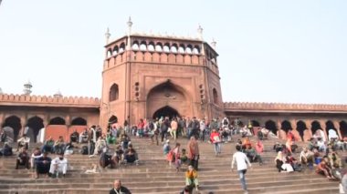 DELHI, Hindistan - 13 Şubat 2018: Jama Mescidi Camii merdivenlerinde birçok insan oturuyor, Jama Mescidi Delhi 'nin en ünlü simgelerinden biri..