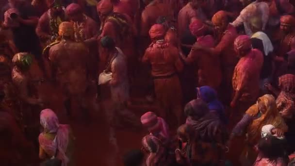 ヒンズー教徒の信者の大群衆は カラフルな粉で遊ぶとクリシュナ寺院でホリを祝うためにお互いの色を投げます — ストック動画