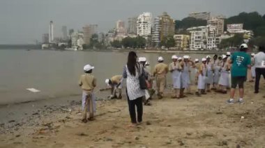 MUMBAI, INDIA, 24 SEPTEMBER 2018: Ganesha 'nın Hint festivali sonrası Güney Mumbai' deki Chaupati Sahili 'ni temizlemek için birbirlerine yardım eden bir grup genç öğrenci. 