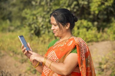 Geleneksel giysili Hintli kadın açık havada akıllı telefon kullanıyor.