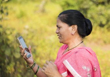 Geleneksel giysili Hintli kadın açık havada akıllı telefon kullanıyor. İnsan hayatı kavramını değiştirmek.