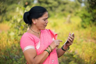 Geleneksel giysili Hintli kadın açık havada akıllı telefon kullanıyor. İnsan hayatı kavramını değiştirmek.