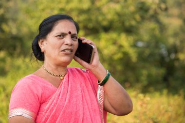 Geleneksel giysili Hintli kadın açık havada akıllı telefon kullanıyor.