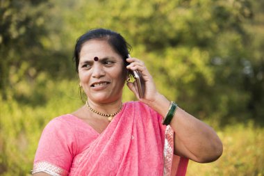 Geleneksel giysili Hintli kadın açık havada akıllı telefon kullanıyor.