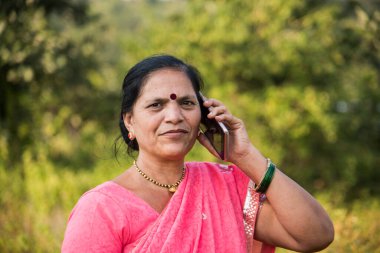 Geleneksel giysili Hintli kadın açık havada akıllı telefon kullanıyor.