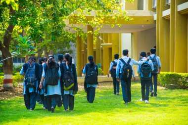 NAGPUR, MAHARASHTRA, INDIA - 9 Nisan 2016: Üniversite kampüsünde kimliği belirsiz genç öğrenciler sırt çantalarıyla birlikte yürüyorlar.