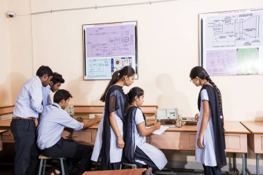 NAGPUR, INDIA - 11 Nisan 2016: Teknoloji öğrencileri araştırma için bilgisayarları kullanarak masada oturuyorlar. Çalışmaları için bilgisayardan bilgi alan gençler. 