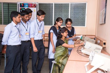 NAGPUR, INDIA - 11 Nisan 2016: Teknoloji öğrencileri araştırma için bilgisayarları kullanarak masada oturuyorlar. Çalışmaları için bilgisayardan bilgi alan gençler. 