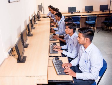 NAGPUR, INDIA - 11 Nisan 2016: Teknoloji öğrencileri araştırma için bilgisayarları kullanarak masada oturuyorlar. Çalışmaları için bilgisayardan bilgi alan gençler. 