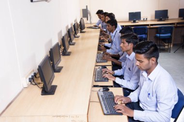 NAGPUR, INDIA - 11 Nisan 2016: Teknoloji öğrencileri araştırma için bilgisayarları kullanarak masada oturuyorlar. Çalışmaları için bilgisayardan bilgi alan gençler. 