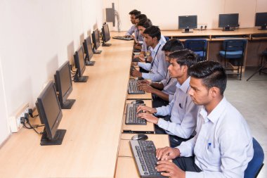 NAGPUR, INDIA - 11 Nisan 2016: Teknoloji öğrencileri araştırma için bilgisayarları kullanarak masada oturuyorlar. Çalışmaları için bilgisayardan bilgi alan gençler. 