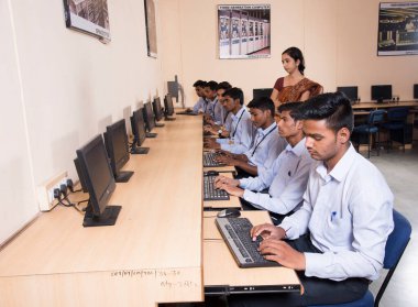 NAGPUR, INDIA - 11 Nisan 2016: Teknoloji öğrencileri araştırma için bilgisayarları kullanarak masada oturuyorlar. Çalışmaları için bilgisayardan bilgi alan gençler. 