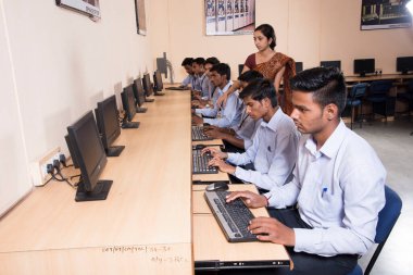 NAGPUR, INDIA - 11 Nisan 2016: Teknoloji öğrencileri araştırma için bilgisayarları kullanarak masada oturuyorlar. Çalışmaları için bilgisayardan bilgi alan gençler. 