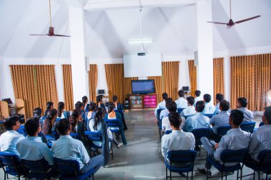 AMRAVATI, MAHARASHTRA, INDIA - 11 Nisan 2016: Üniversitelerinin ses video salonunda belgesel izlemek için birlikte oturan kimliği belirsiz bir grup genç öğrenci.