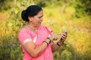 Geleneksel giysili Hintli kadın açık havada akıllı telefon kullanıyor. İnsan hayatını değiştirmek 