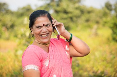 Geleneksel giysili Hintli kadın açık havada akıllı telefon kullanıyor. İnsan hayatını değiştirmek 