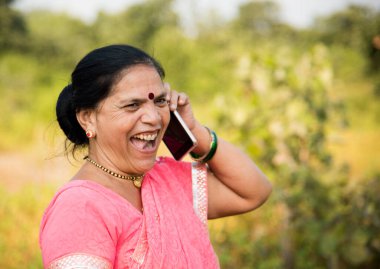 Geleneksel giysili Hintli kadın açık havada akıllı telefon kullanıyor. İnsan hayatını değiştirmek 