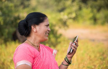 Geleneksel giysili Hintli kadın açık havada akıllı telefon kullanıyor. İnsan hayatını değiştirmek 