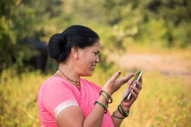 Geleneksel giysili Hintli kadın açık havada akıllı telefon kullanıyor. İnsan hayatını değiştirmek 