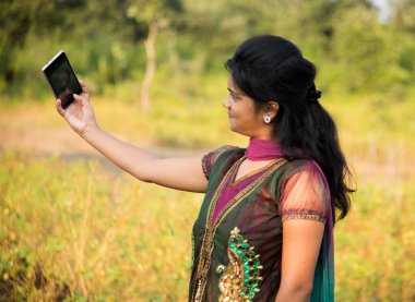 Mutlu genç Hintli kız dışarıda akıllı telefondan selfie çekiyor.. 