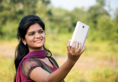 Mutlu genç Hintli kız dışarıda akıllı telefondan selfie çekiyor.. 