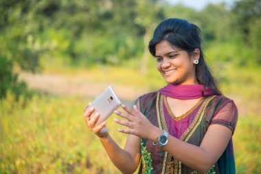 Mutlu genç Hintli kız dışarıda akıllı telefondan selfie çekiyor.. 