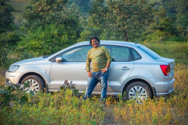 Indian man with his just bought a new car.