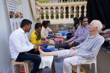 MUMBAI, INDIA, - 5 Şubat 2020: Kimliği belirsiz kör adamlar Mumbai caddesinde turistlere ayak masajı yapıyor.
