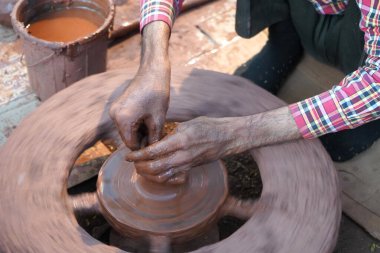 Bir çömlekçinin elleri, tekerleğin üzerinde toprak kavanozu yaratıyor. Kadın ellerine rehberlik eden bir çömlekçi 
