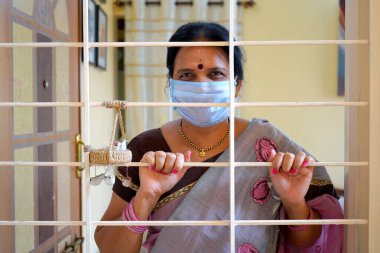 Virüs salgınından korunmak ve evde kalmak için tıbbi koruyucu maskeler takan kadın..