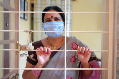 Virüs salgınından korunmak ve evde kalmak için tıbbi koruyucu maskeler takan kadın..