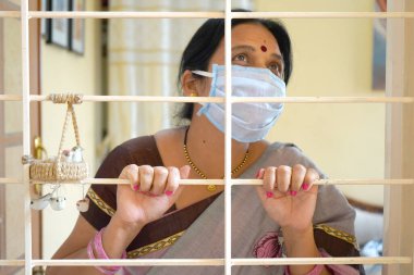 Virüs salgınından korunmak ve evde kalmak için tıbbi koruyucu maskeler takan kadın..