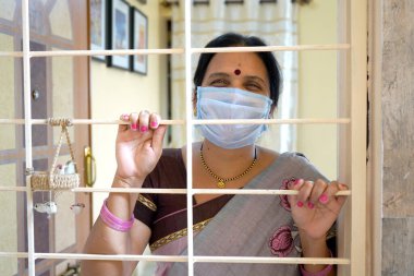 Virüs salgınından korunmak ve evde kalmak için tıbbi koruyucu maskeler takan kadın..