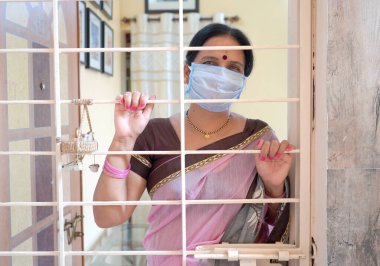 Virüs salgınından korunmak ve evde kalmak için tıbbi koruyucu maskeler takan kadın..
