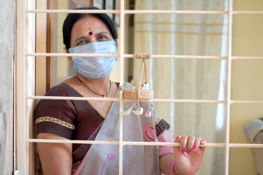 Virüs salgınından korunmak ve evde kalmak için tıbbi koruyucu maskeler takan kadın..