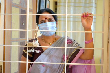 Virüs salgınından korunmak ve evde kalmak için tıbbi koruyucu maskeler takan kadın..