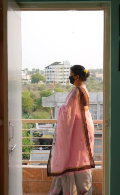 Virüs salgınından korunmak ve evde kalmak için tıbbi koruyucu maskeler takan kadın..