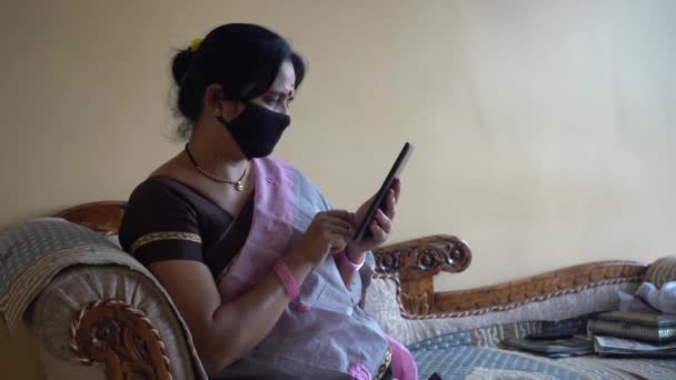 Hinduska Kobieta Masce Ochronnej Czyta Wiadomości Tablecie Podczas Izolacji Domu — Wideo stockowe