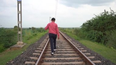 Hindistan tren yolunda yürüyen bir adam.