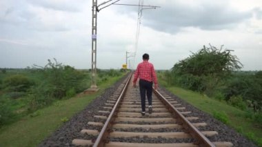Hindistan tren yolunda yürüyen bir adam.