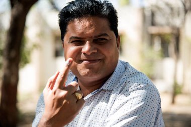 MUMBAI, MAHARASHTRA, INDIA 21 Şubat 2017: İnsanlar, bölgedeki sandık merkezinin önünde oy kullandıktan sonra mürekkep izli parmaklarını gösteriyor.