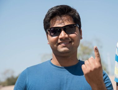 MUMBAI, MAHARASHTRA, INDIA 21 Şubat 2017: İnsanlar, bölgedeki sandık merkezinin önünde oy kullandıktan sonra mürekkep izli parmaklarını gösteriyor.