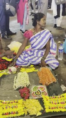 MUMBAI, INDIA, 28 ARALIK 2024: Dadar İstasyonu yakınlarındaki çiçek pazarında satmak için çiçek çelengi yapan kadın