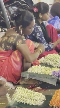 MUMBAI, INDIA, 28 ARALIK 2024: Dadar İstasyonu yakınlarındaki çiçek pazarında satmak için çiçek çelengi yapan kadın