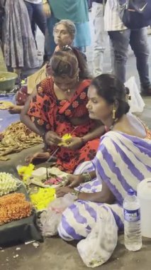 MUMBAI, INDIA, 28 ARALIK 2024: Dadar İstasyonu yakınlarındaki çiçek pazarında satmak için çiçek çelengi yapan kadın