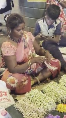 MUMBAI, INDIA, 28 ARALIK 2024: Dadar İstasyonu yakınlarındaki çiçek pazarında satmak için çiçek çelengi yapan kadın