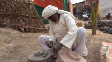 NAGPUR, MAHARASHTRA, INDIA, 25 Ocak 2023: Köy caddesinde geleneksel taş öğütücüsünü yapan adam.