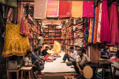 JAIPUR, INDIA 13 AĞUSTOS 2019: Geleneksel sari ve kumaş satan tüccarlar, Jaipur, Jaipur, Hindistan 'ın geleneksel doğu el sanatları merkezidir