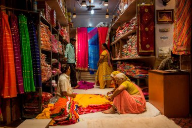 JAIPUR, INDIA 13 AĞUSTOS 2019: Geleneksel sari ve kumaş satan tüccarlar, Jaipur, Jaipur, Hindistan 'ın geleneksel doğu el sanatları merkezidir
