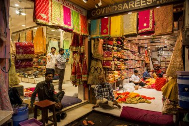 JAIPUR, INDIA 13 AĞUSTOS 2019: Geleneksel sari ve kumaş satan tüccarlar, Jaipur, Jaipur, Hindistan 'ın geleneksel doğu el sanatları merkezidir